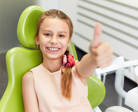girl giving thumbs up after child dentistry appointment