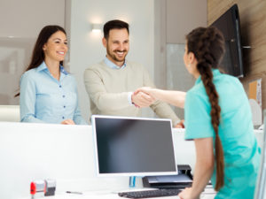 couple at dentist front desk shaking hands