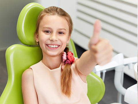girl in dentist chair giving thumbs up