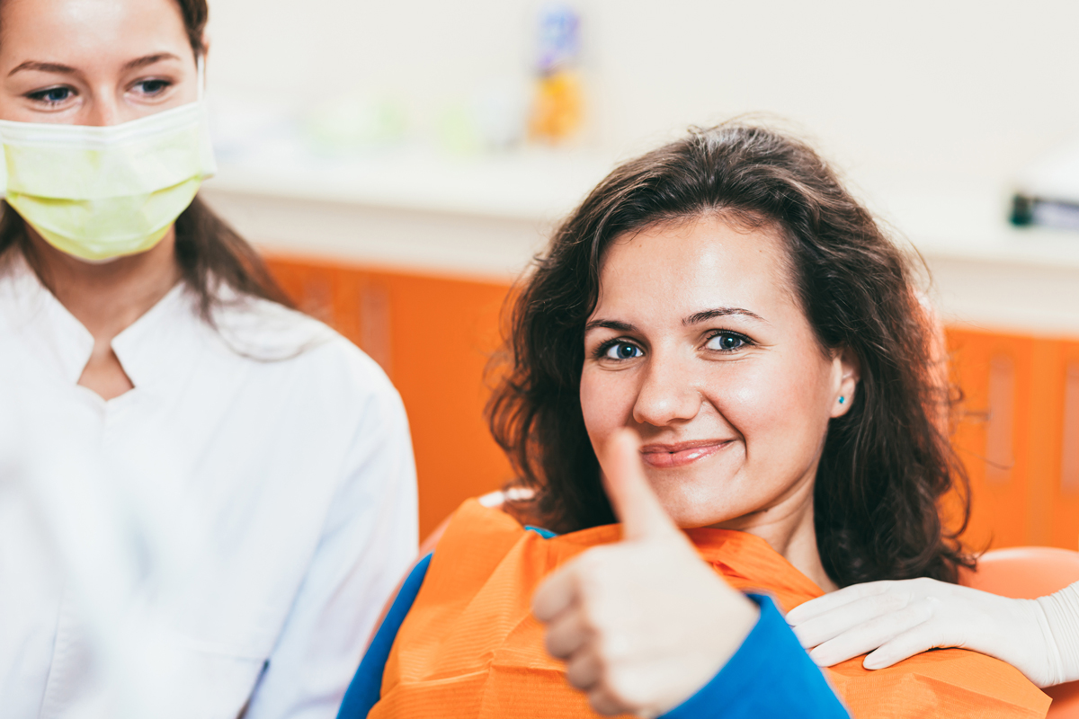 A teen giving the thumbs up from the dentist's chair.